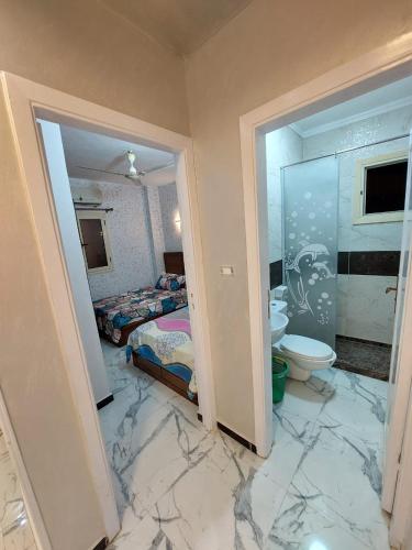 ein Schlafzimmer mit Marmorboden und ein Badezimmer mit Toilette in der Unterkunft فيلا جميل جداا in Dawwār Abū Maḩrūs