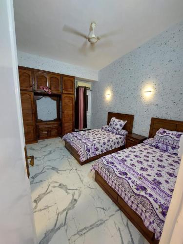 2 Betten in einem Zimmer mit Marmorboden in der Unterkunft فيلا جميل جداا in Dawwār Abū Maḩrūs