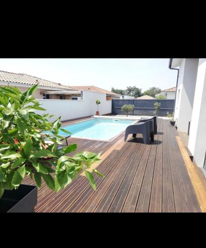 une terrasse en bois avec une piscine et un banc dans l'établissement Maison cosy proche forêt, à Saint-Vincent-de-Paul