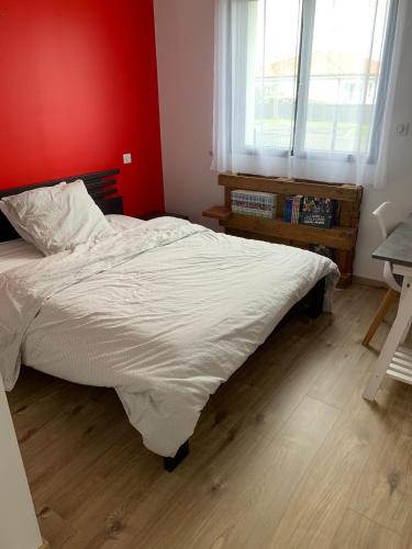 Un dormitorio con una cama grande con una pared roja. en Maison cosy proche forêt, en Saint-Vincent-de-Paul