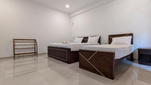 a bedroom with two beds and a chair at Dutch Villa - Trincomalee in Trincomalee
