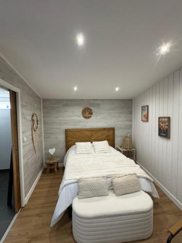 a bedroom with a large white bed with a ottoman at Wimdream , havre de paix cosy, à deux pas de la mer et du centre ville in Wimereux