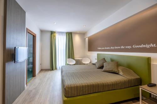 a bedroom with a green bed and a tv at Hotel Ideal in Sirmione