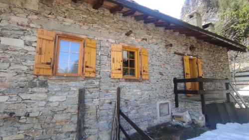 a stone house with wooden windows and a fence at La Baita di Savara - nature and silence in Valsavarenche
