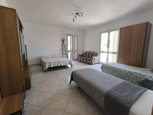 a bedroom with two beds and a couch and a chair at casavacanza la vite in Alezio