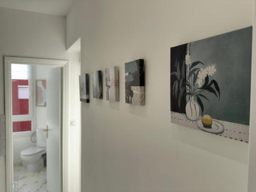 une salle de bain avec une rangée de tableaux sur le mur dans l'établissement Panoramic Sea View Studio, à Cagnes-sur-Mer