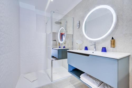 a white bathroom with a sink and a mirror at Hotel Espadon bleu in Le Lavandou
