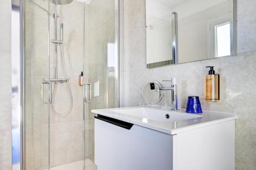 a white bathroom with a sink and a shower at Hotel Espadon bleu in Le Lavandou