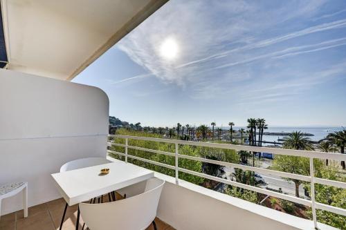 a balcony with a white desk and a view of the ocean at Hotel Espadon bleu in Le Lavandou