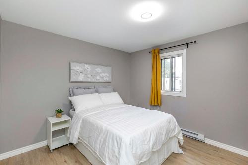 a bedroom with a white bed and a window at Three bedroom apartment Free parking EV charger in Longueuil
