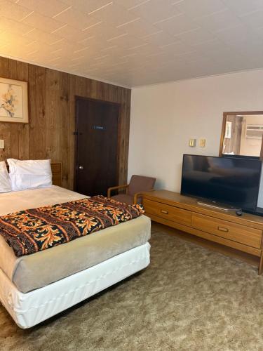 a hotel room with a bed and a flat screen tv at Prairie winds motel in Carthage