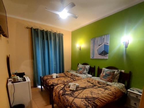two beds in a room with green walls at Guest House Capitao Mor in Faro