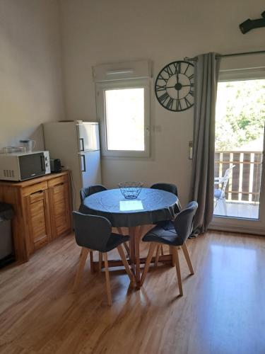 une salle à manger avec une table, des chaises et une horloge dans l'établissement Appartement tout confort, à Brides-les-Bains