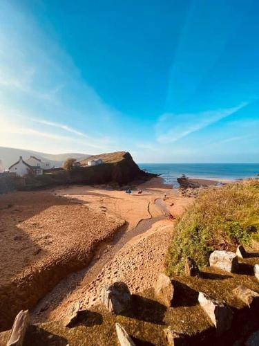 a beach with rocks and the ocean in the background at The Bell Ringers Cottage in Loddiswell