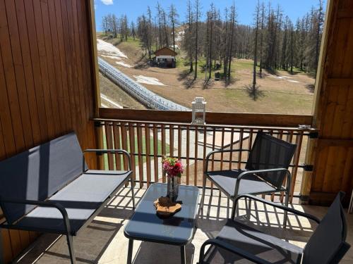 a balcony with two chairs and a table with flowers on it at Christiana studios en hyper centre de Valberg aux pieds des pistes in Valberg