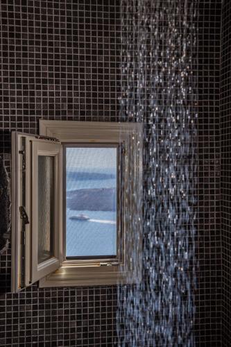a window in a bathroom with a view of the ocean at Mardanza Krokos Suites in Imerovigli
