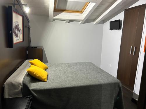a bedroom with a bed with yellow pillows on it at EL Hotelito in Alija del Infantado