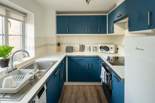 a kitchen with blue cabinets and a sink at Loughton Hideaway: Cozy 1BD Near Tube & Nature in Theydon Bois