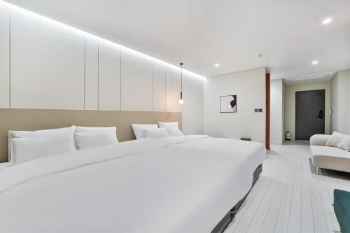 a white bedroom with a large bed and a couch at 호텔그랑파리 in Gwangju