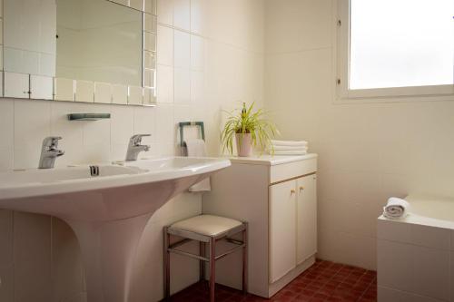 - une salle de bains blanche pourvue d'un lavabo et d'un tabouret dans l'établissement Le Jardin d'Eden, à Château-Thierry
