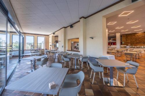 a cafeteria with tables and chairs and windows at Hotel Ideal in Sirmione
