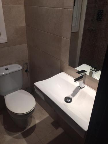 a bathroom with a white toilet and a sink at La Perla in Almería