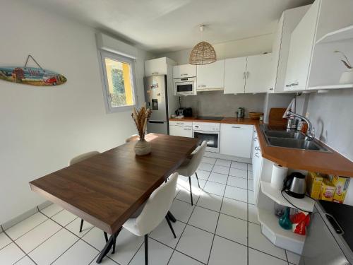 une cuisine avec une table en bois et des armoires blanches dans l'établissement Appartement T3 à Bayonne avec terrasse de 14 m2, à Bayonne