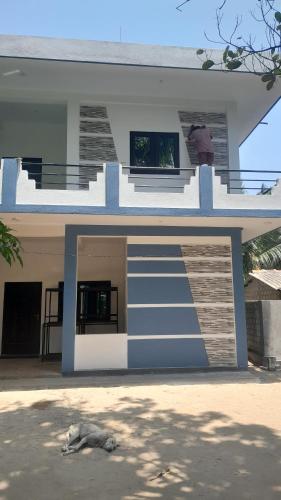 a blue and white house with a dog laying on the ground at Theepan's Home in Nilaveli