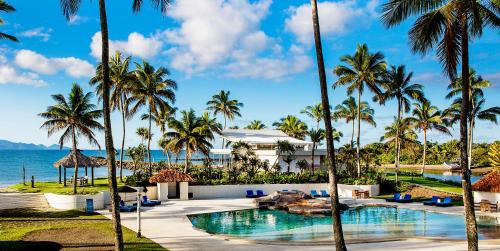 パシフィック・ハーバーにあるThe Pearl South Pacific Resort, Spa & Golf Courseのヤシの木とスイミングプールのあるリゾートの景色を望めます。