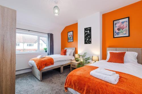 two beds in a room with orange walls at Stylish 3 Bedroom Home with Driveway, Family and Business Friendly in Mold