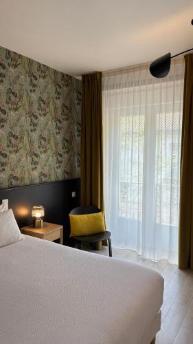 une chambre avec un lit, une chaise et une fenêtre dans l'établissement Logis Hôtel Restaurant Grand Hôtel de Lyon, à Vals-les-Bains