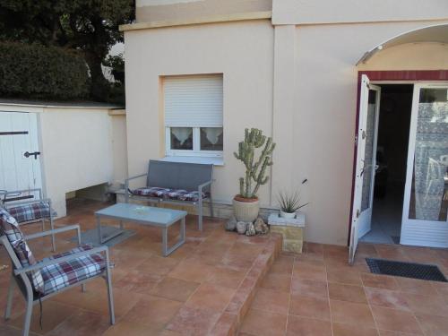 a patio with a couch and a table and a cactus at Villeneuve Loubet Studio 4 p rez de jardin a 5 mn de la mer in Villeneuve-Loubet