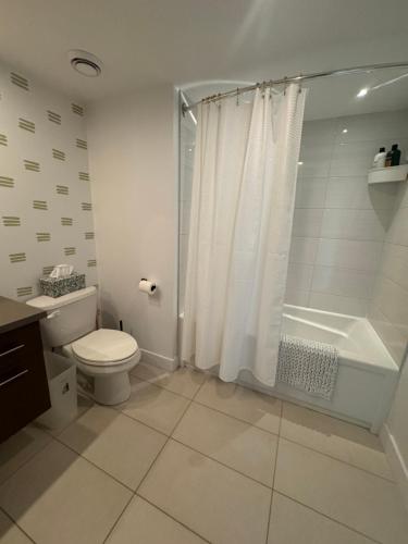 a white bathroom with a toilet and a shower at Le Haven in MSA in Beaupré