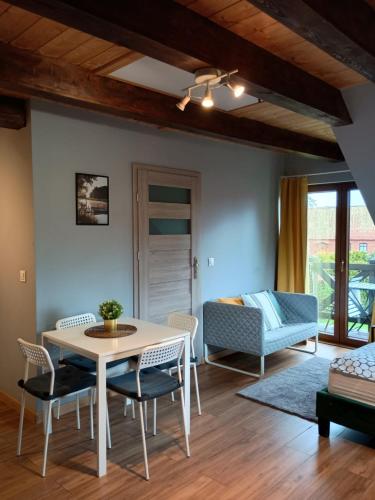 a living room with a table and chairs and a couch at Mazurska Apartamenty in Rydzewo