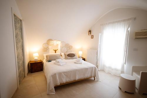 a white bedroom with a bed and a large window at Voltebianche in Martina Franca