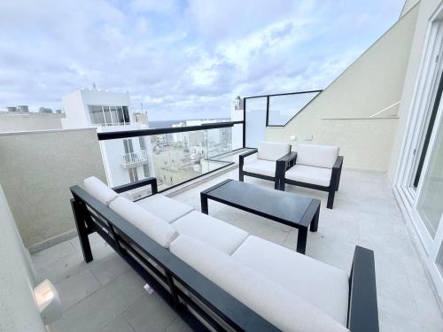 a balcony with white couches and chairs on a building at The Bugibba Central Penthouse! in St Paul's Bay