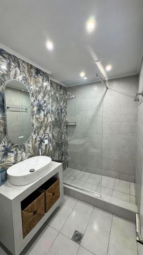 un bagno con doccia, lavandino e specchio di Anemos Deluxe Poseidi Apartments a Possidi