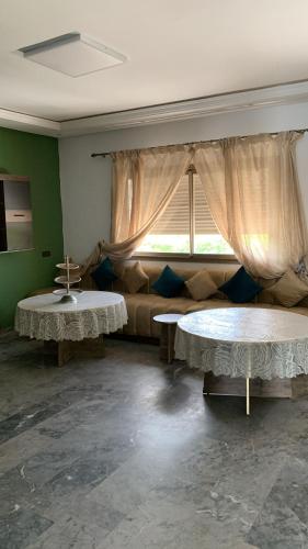 two tables in a room with a couch and a window at Residence amwaj in Douar el Arbi Ben Ahmed