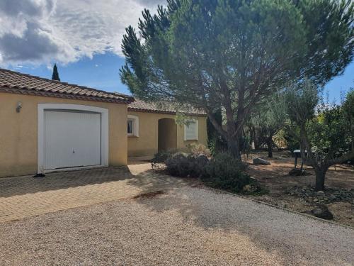 une maison avec un arbre et un garage blanc dans l'établissement Villa de l Ode, à Mirepeisset