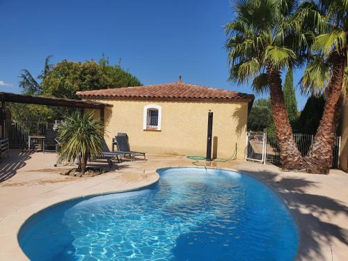 une piscine devant une maison avec des palmiers dans l'établissement Villa de l Ode, à Mirepeisset