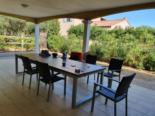 une table et des chaises en bois sur une terrasse dans l'établissement Villa de l Ode, à Mirepeisset