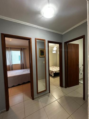 a room with two mirrors and a bedroom with a bed at Apartamendo Marina Clube in São Pedro da Aldeia