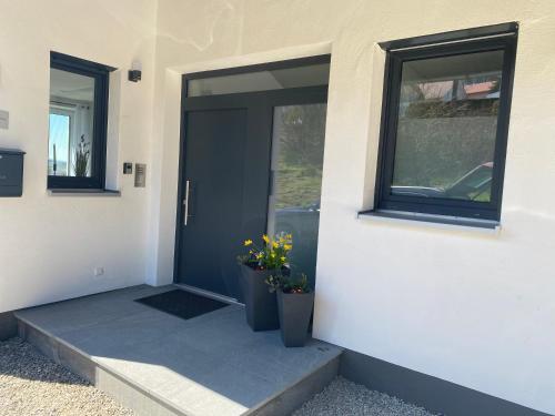 a front door of a house with two vases of flowers at FeWo Günztalblick - Ruhige Lage -125 qm - neu und komfortabel - große Terrasse in Frickenhausen