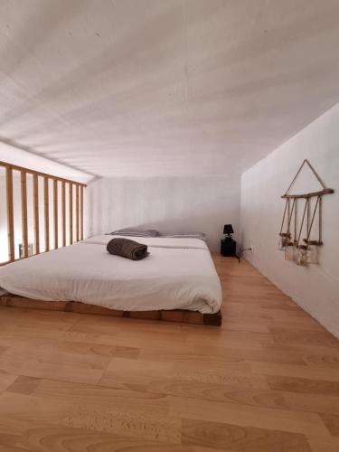 une chambre avec un grand lit dans une pièce blanche dans l'établissement Loft studio avec mezzanine, limitrophe Monaco, à Roquebrune-Cap-Martin