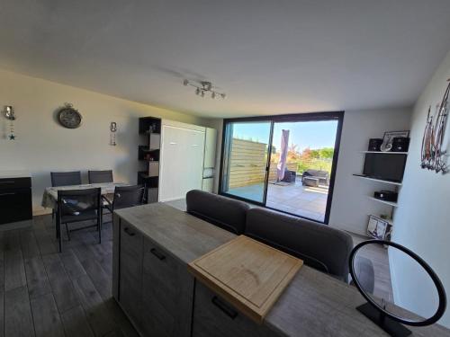 un salon avec une table et une grande fenêtre dans l'établissement Appartement Lavoisier, à La Rochelle