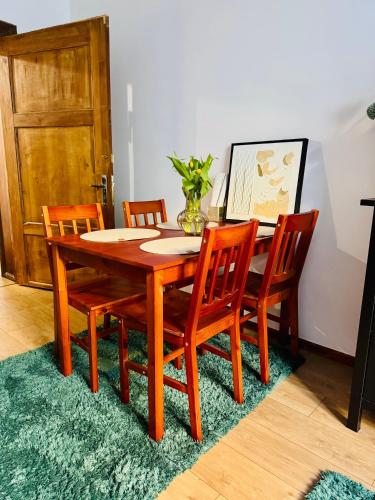 a wooden dining room table with four chairs and a vase at Mazurska in Barczewo