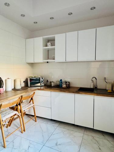 a kitchen with white cabinets and a table and chairs at Mazurska in Barczewo