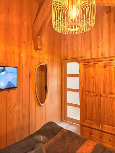 a room with a wooden wall with a mirror and a chandelier at Chalet Des Charmes in Thollon
