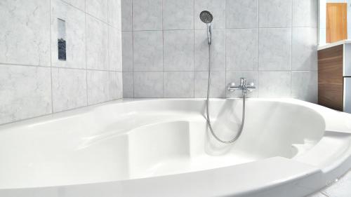 a white bath tub with a shower in a bathroom at Familienappartement Seppenbauer in Bad Ischl