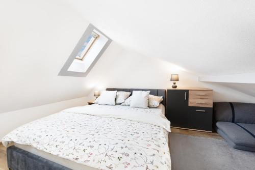 a white bedroom with a bed and a chair at Wellness Apartmány Andrea in Zdíkov